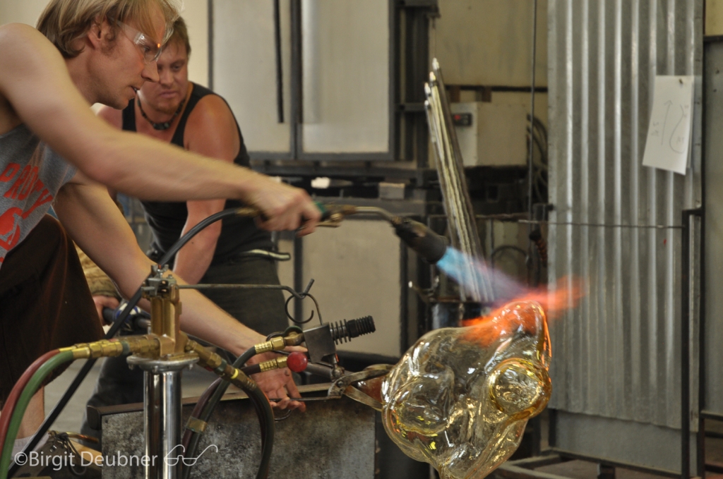 Jason torching the large glass body cast to keep it at even temperature to protect it from cracking before it can be placed into the annealer for a day long, controlled cooling process.. Project by Glass Artist: Ivan Mora
